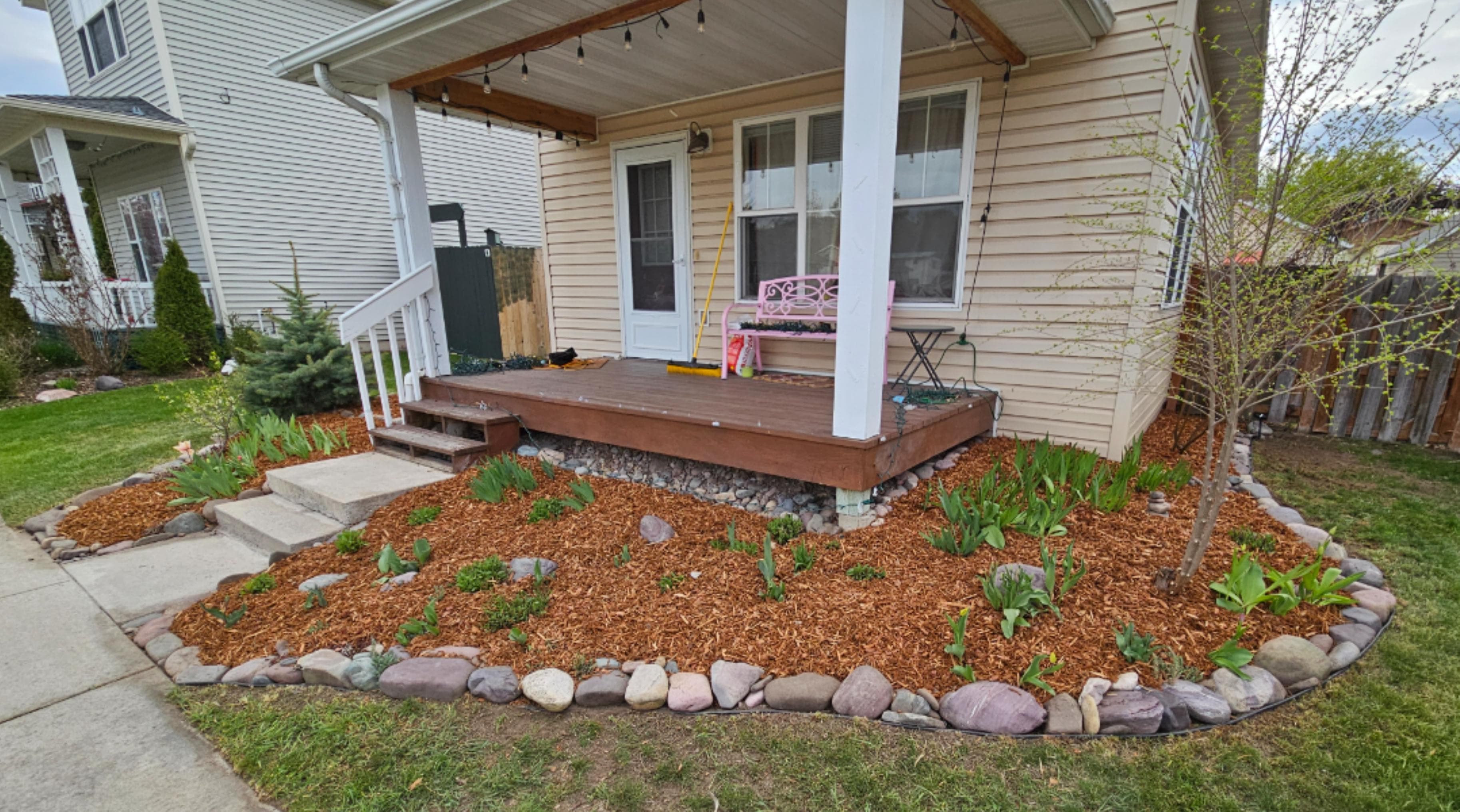 Cozy front porch with landscaped flower beds and mulch, perfect for outdoor relaxation.