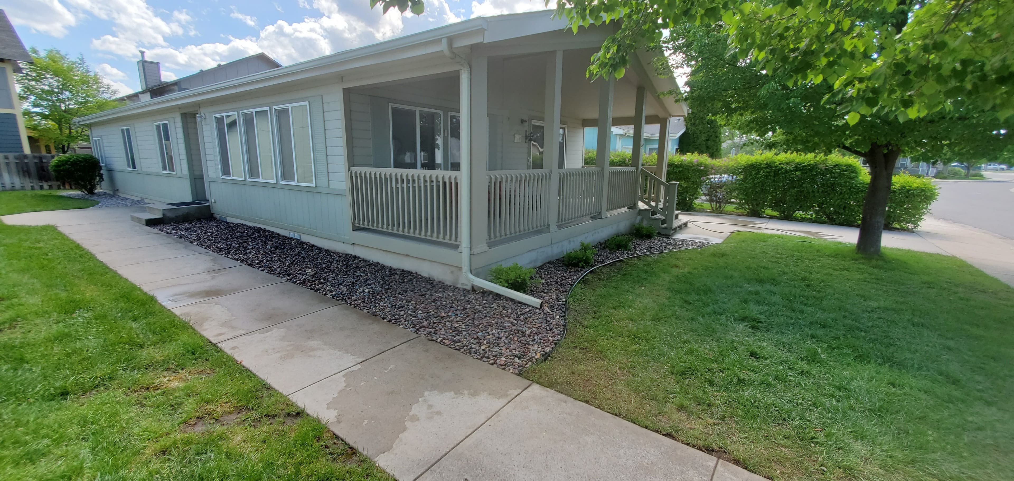 House exterior with porch, landscaped yard, and clear blue sky. Pathway leads to entrance.