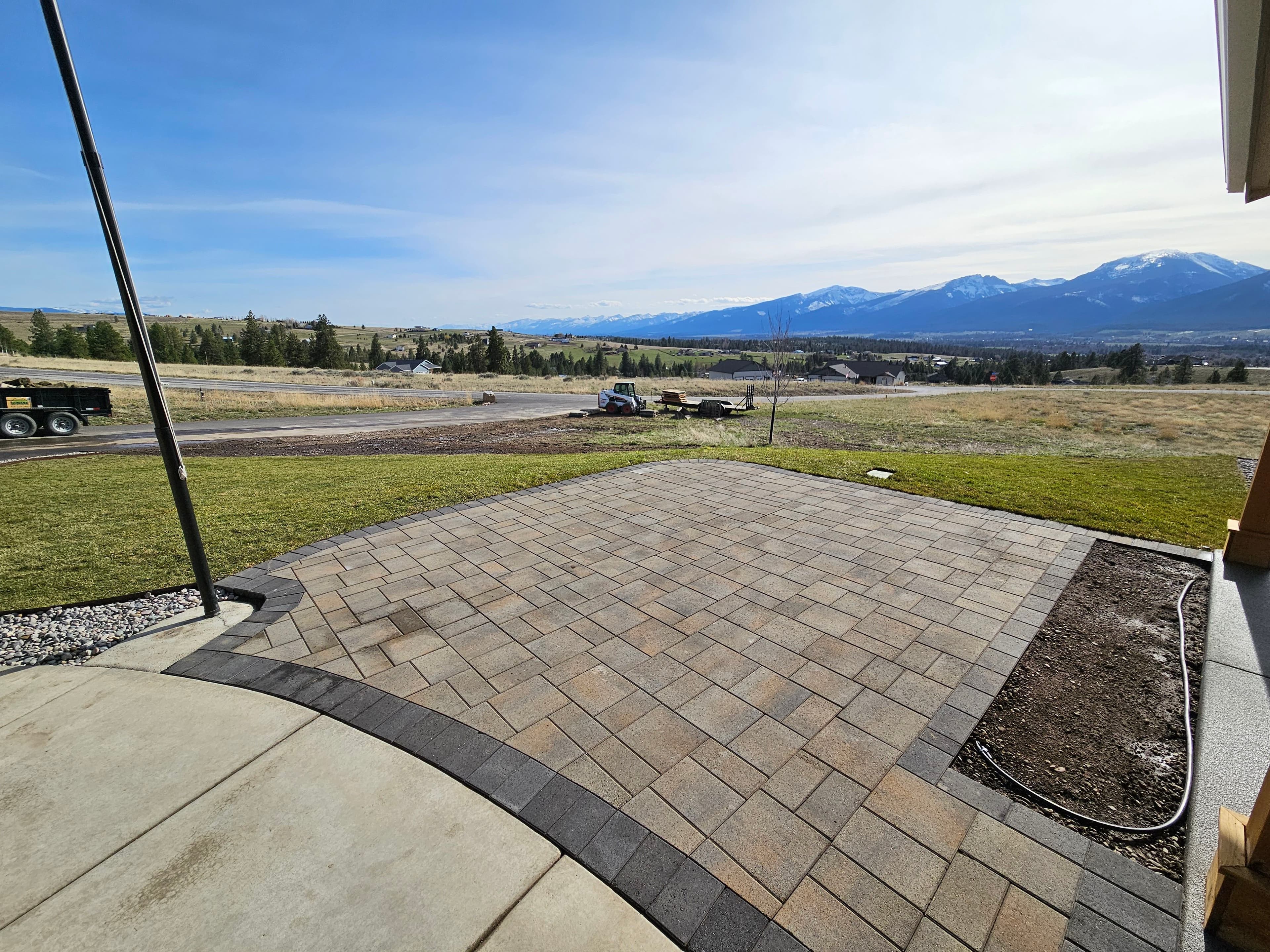 Patio with paver stones overlooking a scenic mountain view and landscaped yard.